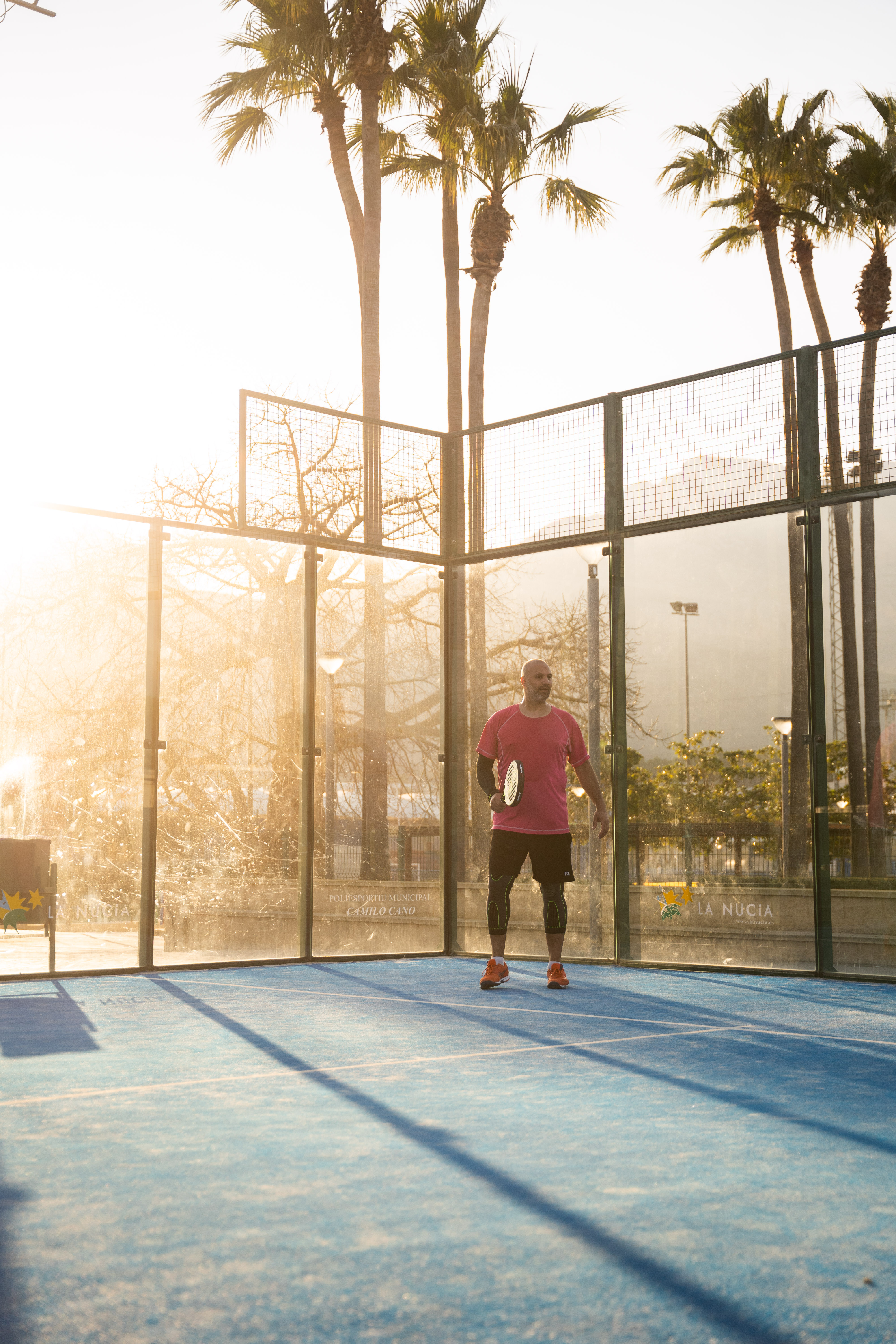 Padelbane med palmer og solnedgang